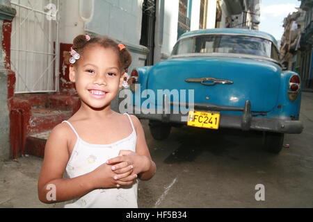 Jolie petite fille debout devant une voiture d'époque dans une rue de La Havane, Cuba, Caraïbes, Amériques Banque D'Images