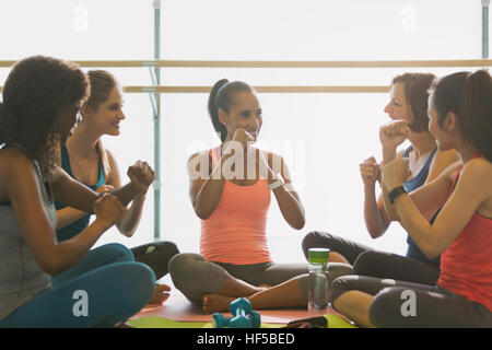 Les femmes faisant des gestes avec les poings en classe d'exercice fitness studio Banque D'Images
