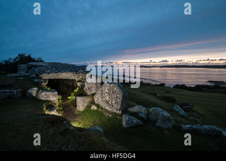 Bants Carn chambre funéraire éclairée par flash comme le soleil se couche à l'horizon, St Mary, Îles Scilly Banque D'Images