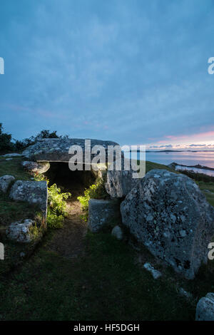 Bants Carn chambre funéraire éclairée par flash comme le soleil se couche à l'horizon, St Mary, Îles Scilly Banque D'Images