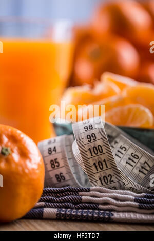 Fruits tropicaux frais et de mesurer les bandes.Tangerines, peeled tangerine et tranches de mandarine sur un tissu bleu. Le jus de mandarine. Banque D'Images