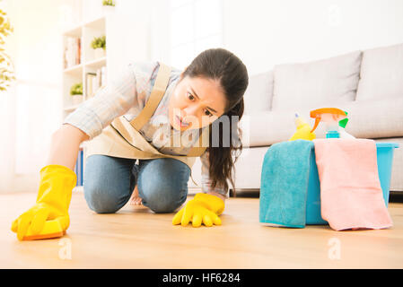 Femme au foyer à peine plancher nettoyage nettoyage en lutte avec des gants de l'expression face à genoux sur sol en bois à la maison. mixed race chinoise asiatique m Banque D'Images