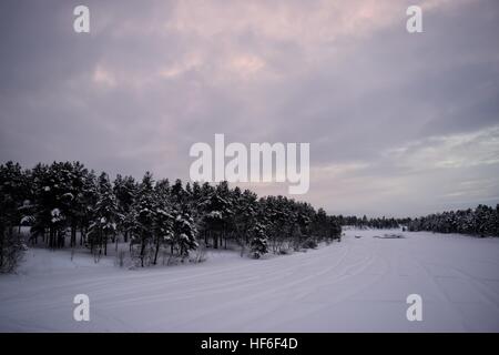 Assombri Coucher de soleil sur un lac gelé Inari, Finlande Banque D'Images