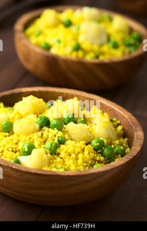 Couscous au curry avec des petits pois, le chou-fleur, le gingembre et l'ail servi dans des bols en bois, photographiés avec lumière naturelle Banque D'Images