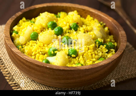 Couscous au curry avec des petits pois, le chou-fleur, le gingembre et l'ail servi dans un bol en bois, photographiés avec lumière naturelle Banque D'Images