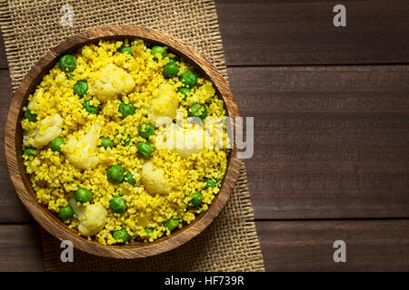 Couscous au curry avec des petits pois, le chou-fleur, le gingembre et l'ail servi dans bol en bois, frais généraux photographié avec une lumière naturelle Banque D'Images