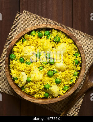 Couscous au curry avec des petits pois, le chou-fleur, le gingembre et l'ail servi dans bol en bois, frais généraux photographié avec une lumière naturelle Banque D'Images