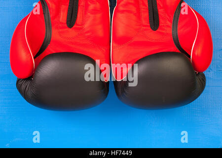 Gants de boxe rouge et noir sur un bureau en bois bleu Banque D'Images