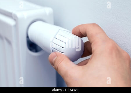La main de l'homme l'ajustement de la température du radiateur. Banque D'Images