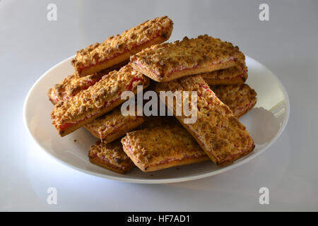 Des biscuits avec de la confiture de fraise sur une plaque blanche Banque D'Images