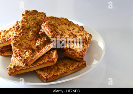 Des biscuits avec de la confiture de fraise sur une plaque blanche Banque D'Images