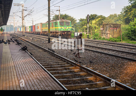 Vieil homme tente de traverser les voies ferrées à l'avant d'un train de marchandises en gare dans le sud de Kolkata, Inde. Banque D'Images