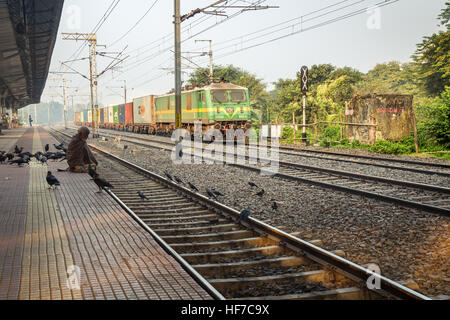 Train de marchandises des chemins de fer indiens traversant une gare déserte plate-forme sur un matin d'hiver brumeux. Banque D'Images