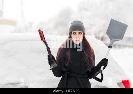 Fille avec la pelle et brosse à enlever la neige de la voiture Banque D'Images