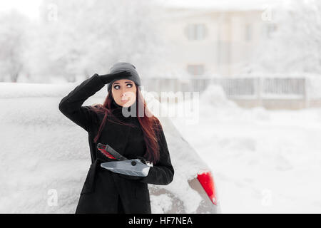 Fille avec la pelle et brosse à enlever la neige de la voiture Banque D'Images