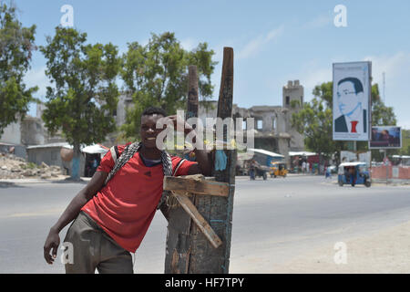 Un homme se tient sur le côté de la route au centre-ville de Mogadiscio, en face d'un panneau pour candidate présidentielle Jabril Ibrahim Abdulle le 25 septembre 2016. Photo ONU / Tobin Jones Banque D'Images