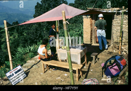 Les randonneurs prennent un repos sur une pente de montagne au-dessus de la vallée de Pokhara au Népal. L'image capture le terrain montagneux et les vues pittoresques de la vallée, avec des randonneurs prenant une pause pendant leur voyage. Banque D'Images