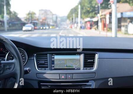 Vue depuis l'intérieur d'une voiture sur une partie du tableau de bord avec une unité de navigation et troubles de rue en face d'une voiture Banque D'Images