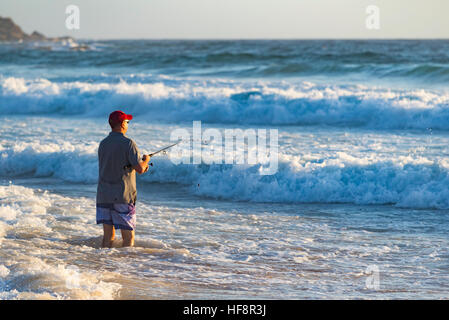 Un homme plus âgé debout sur une plage de pêche dans le surf avec une canne à pêche de plage sur une plage de Sydney tôt un matin d'été en Australie Banque D'Images