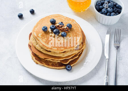 Pile de crêpes aux bleuets frais, noix et miel sur plaque blanche. Petit déjeuner santé alimentation. Banque D'Images