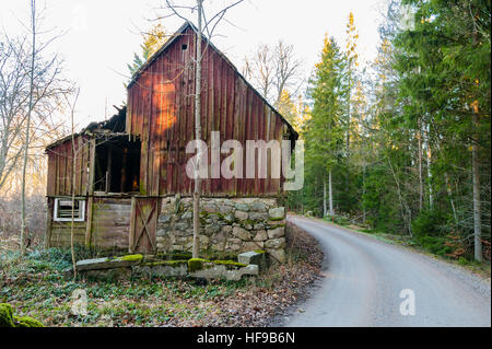 Ancienne ferme et grange abandonnée ou à côté d'une route de campagne et de forêts. Emplacement du sud de la Suède. Banque D'Images