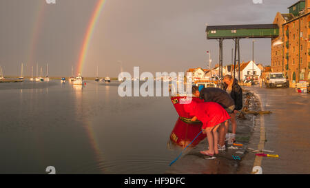 En crabe sur le mur du port comme un arc-en-ciel se forme au-dessus de Wells-next-the-Sea au cours d'une soirée d'orage. Banque D'Images