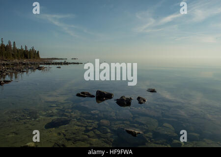 Calme plat après-midi libre de Clear Lake Huron et de l'eau des roches calcaires le long du littoral. Les nuages qui reflète de manière zign zag. Banque D'Images