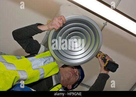 Mesurer avant l'installation de la climatisation conduits par technicien en bureau commercial de plafond Banque D'Images