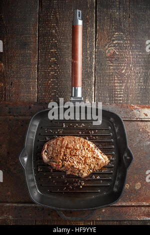 Roast beef steak dans les épices sur grill pan sur la table verticale Banque D'Images