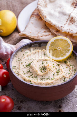 Dans l'Humus bol fait maison avec du citron, des tomates et chapation bureau en bois naturel. Banque D'Images