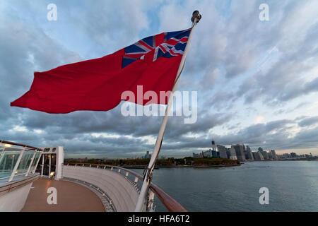 Ensign britannique red ensign battant sur le pont du navire de croisière Queen Mary 2 avec New York city skyline en arrière-plan Banque D'Images