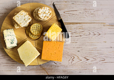 Sélection de fromages sur un plateau à fromage rond, assis sur une vieille table. Banque D'Images