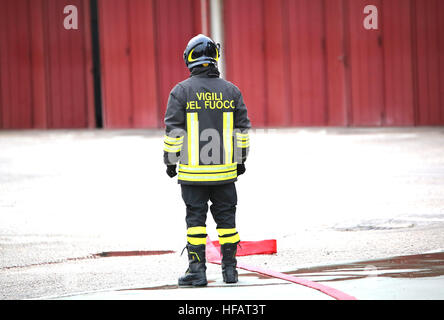 Les pompiers italiens lonely avec le tuyau d'incendie rouge avec les mots dans l'vêtements de protection des pompiers cela signifie en langue italienne Banque D'Images