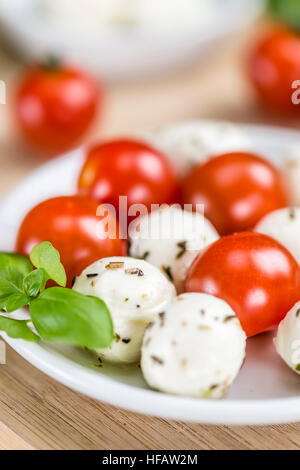 Les tomates et la mozzarella avec le basilic (selective focus) sur une vieille table en bois Banque D'Images