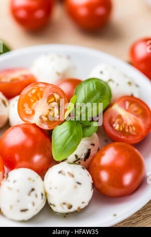 Les tomates et la mozzarella avec le basilic (selective focus) sur une vieille table en bois Banque D'Images