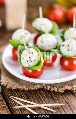 Les tomates et la mozzarella avec le basilic (selective focus) sur une vieille table en bois Banque D'Images