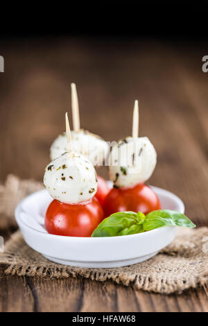 Les tomates et la mozzarella avec le basilic (selective focus) sur une vieille table en bois Banque D'Images