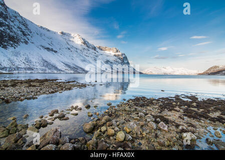 Les pierres par la mer froide avec des sommets enneigés en arrière-plan de Tromso, Norvège Banque D'Images