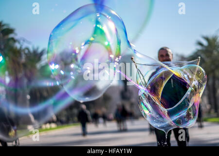Un homme fait une énorme bulle de savon dans un parc. Banque D'Images