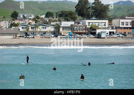 Les surfeurs et Stand Up Paddle Boarders en attente d'une vague sur la plage à Cayucos, California, USA Banque D'Images