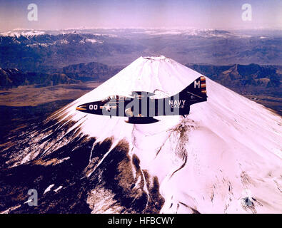 Un avion de chasse Grumman F9F Panther du Carrier Air Group 2 vole en formation près d'un volcan enneigé, démontrant les capacités de réaction, la manœuvrabilité et la disponibilité opérationnelle des avions à réaction embarqués lors d'exercices d'entraînement au milieu des années 1950 Banque D'Images