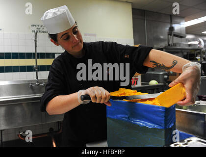 La Marine américaine spécialiste culinaire 3 Classe Alisha VanMeir coupe un bloc de fromage cheddar, tout en préparant le déjeuner au restaurant All-American et cuisine dans Station Navale Everett, Washington, 19 septembre 2012. La cuisine sert des repas pour servir ses membres, le ministère de la défense des personnel et des retraités. (U.S. Photo par marine Spécialiste de la communication de masse de la classe 3ème Jonathan A./côlon) Parution de l'activité canalisation 120919-N-FR671-004 Banque D'Images