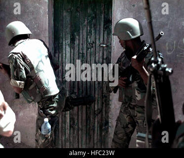 Deux membres de Forces de défense du Botswana se tenir près d'une porte d'un bâtiment. Le soldat à gauche donne un coup à la porte avec sa jambe droite. La porte fait partie d'un bâtiment dans le marché de Bakara à Mogadiscio, en Somalie. Les soldats sont à la recherche d'armes pendant un raid sur le marché avec des Marines (non illustré). Cette mission est en appui direct à l'Opération Restore Hope. 2 soldats BDF sur raid in Bakaara Market 1993-01-30 Banque D'Images