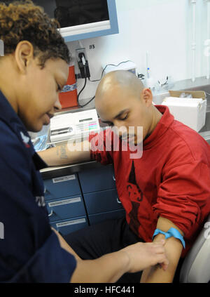 Maître de 2e classe Delita Tolbert, hôpital corpsman, prend un échantillon de sang d'un marin lors d'un appel à volontaires pour le programme de la banque de sang à bord du porte-avions de classe Nimitz USS Carl Vinson. Carl Vinson et Carrier Air Wing 17 mènent l'aide humanitaire et des opérations de secours en Haïti en réponse au séisme, 12 janvier. L'aide humanitaire et des opérations de secours en Haïti 240629 Banque D'Images