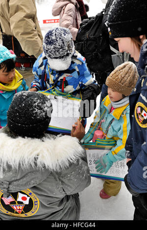 Le chef Billy Honor Harger, originaire de Pearl City, Missouri, montre quelques enfants de l'école japonaise où se trouve sa ville natale, le 5 février 2014. Honor Harger est le chef de l'équipe de la marine 2014, l'équipe de sculpture sur neige de Misawa qui est à Hokkaido, Japon, participant à la 65e Sapporo Snow Festival. L'équipe sculpte un frosty, 3-D version de la U.S. Navy Seabee's 'Bee' Combat logo. C'est la 31e année que Naval Air Facility Misawa et ses commandes de locataires ont envoyé une délégation de marins à Sapporo pour créer une sculpture, et de servir comme ambassadeurs de bonne volonté de l'US Navy. Le festival attire environ 2 milli Banque D'Images