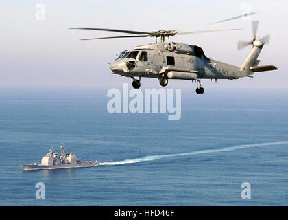 Un hélicoptère SH-60F Seahawk du Helicopter anti-Submarine Squadron HS-11 passe devant le croiseur à missiles guidés USS Leyte Gulf (CG 55) lors des opérations du groupe de frappe de porte-avions dans l'océan Atlantique. L'image capture la capacité anti-sous-marine aéroportée à voilure tournante opérant en formation avec des combattants de surface lors d'un déploiement en cours. Banque D'Images