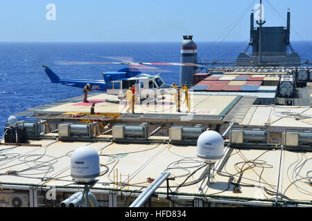 Les membres de l'équipage porter un tuyau d'incendie sur l'hélisurface à bord du navire MV Cape Ray (T-AKR 9679) dans la mer Méditerranée comme une chute d'hélicoptère cargo le 4 août 2014. Le gouvernement des États-Unis à 100 Cape Ray a été modifié et déployés à l'est de la Mer Méditerranée pour disposer d'agents chimiques syriennes conformément au cadre convenu de la Syrie à la fin de 2013. (U.S. Photo par marine Spécialiste de la communication de masse Seaman Desmond Parcs/libérés) agents chimiques syriennes destruction 140804-N-XB010-006 Banque D'Images