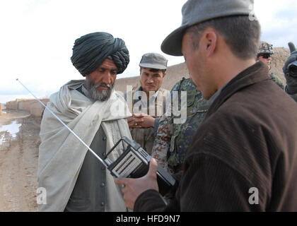 GURESHK--Afghanistan, un agent de la Police nationale afghane donne un GURESHK avec clé à la radio radio à un résident de l'Afghane Mayai Village dans le district de la Province d'Helmand Gureshk sur le 26 janvier 2009. La station de radio opère à partir d'une base d'opérations avancée : et transmet les nouvelles, les messages importants, des prières et de la musique à la 3000 les résidents locaux afghans qui ont été fournies par les radios International Security Assistance Force (ISAF) les troupes opérant à partir de l'Helmand Task Force. Photo de la FIAS par U.S. Navy Maître de 2e classe X. Aramis Ramirez (publié) agent de police afghans les mains hors ra Banque D'Images