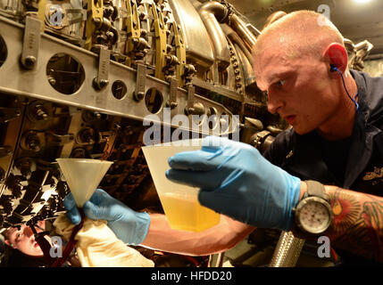 La Marine américaine Technicien en système de turbine à gaz (mécanique) 2e classe Jason Grand verse de l'huile fraîche dans un moteur au cours de l'entretien de routine à bord du destroyer lance-missiles USS Sterett (DDG 104) tout en participant à l'opération inhérents résoudre dans l'5e Flotte des États-Unis zone de responsabilité 18 oct., 2014. Le président Barack Obama a autorisé l'acheminement de l'aide humanitaire à l'Iraq, ainsi que des frappes aériennes ciblées pour protéger le personnel américain de la part des extrémistes connus sous le nom de l'État islamique en Irak et au Levant. Le Commandement central américain dirigé les opérations. (U.S. Photo par marine Spécialiste de la communication de masse de la classe de 3ème Banque D'Images