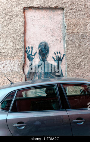 Street art troublant astucieux d'une personne crier à travers une fenêtre dans un mur, au-dessus d'une voiture garée sur un mur, Madrid Banque D'Images